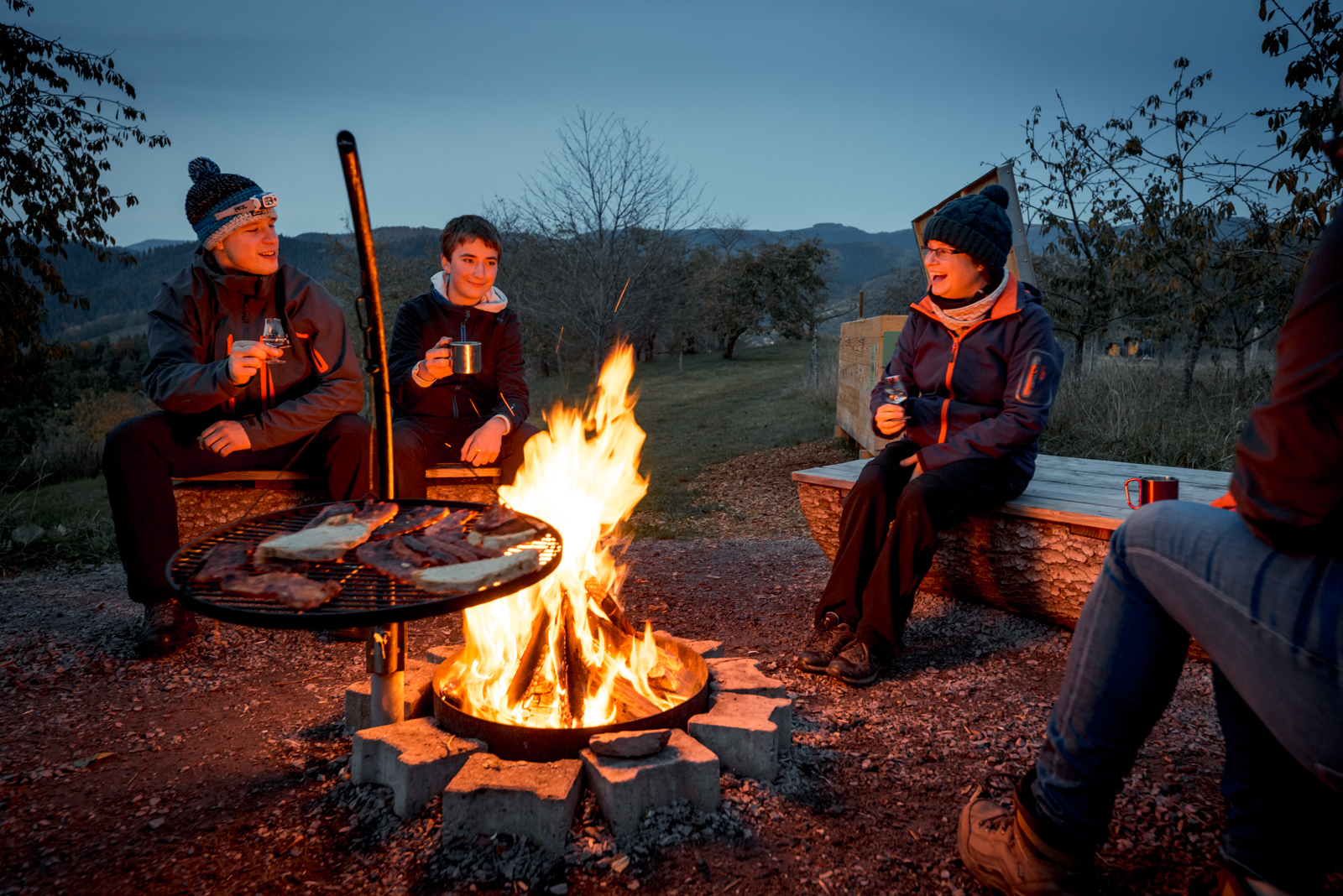  3 Personen sitzen am Lagerfeuer im Trekking Camp