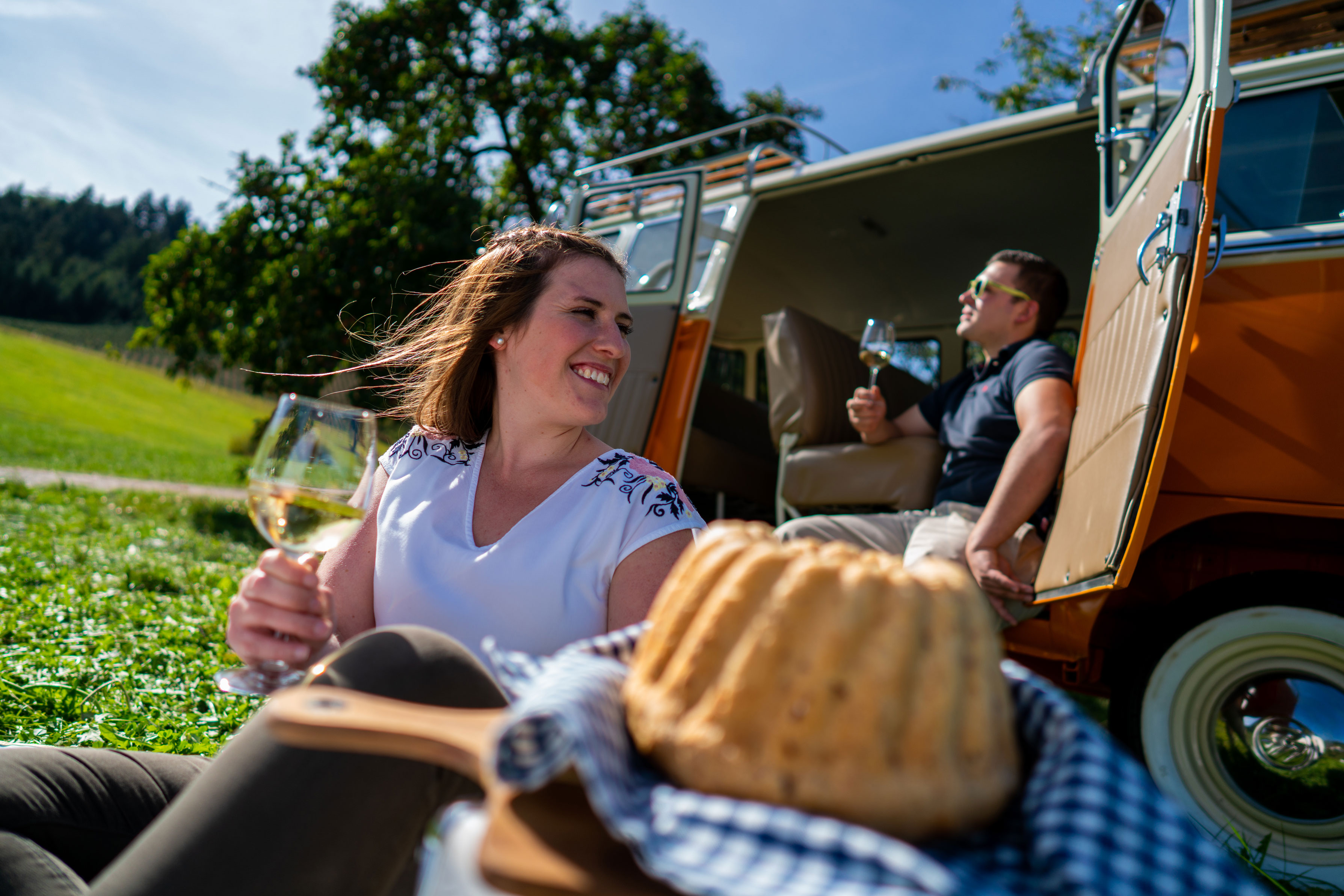 Pärchen beim Picknick auf der Wiese mit VW Bulli
