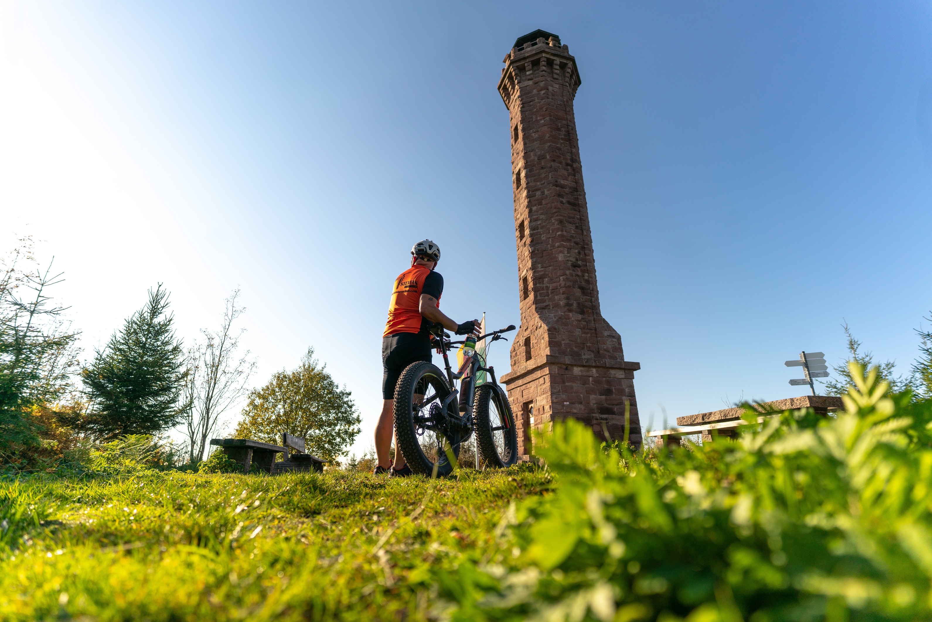 Fahrer des Fatbikes steht neben dem Rad und vor dem Moosturm