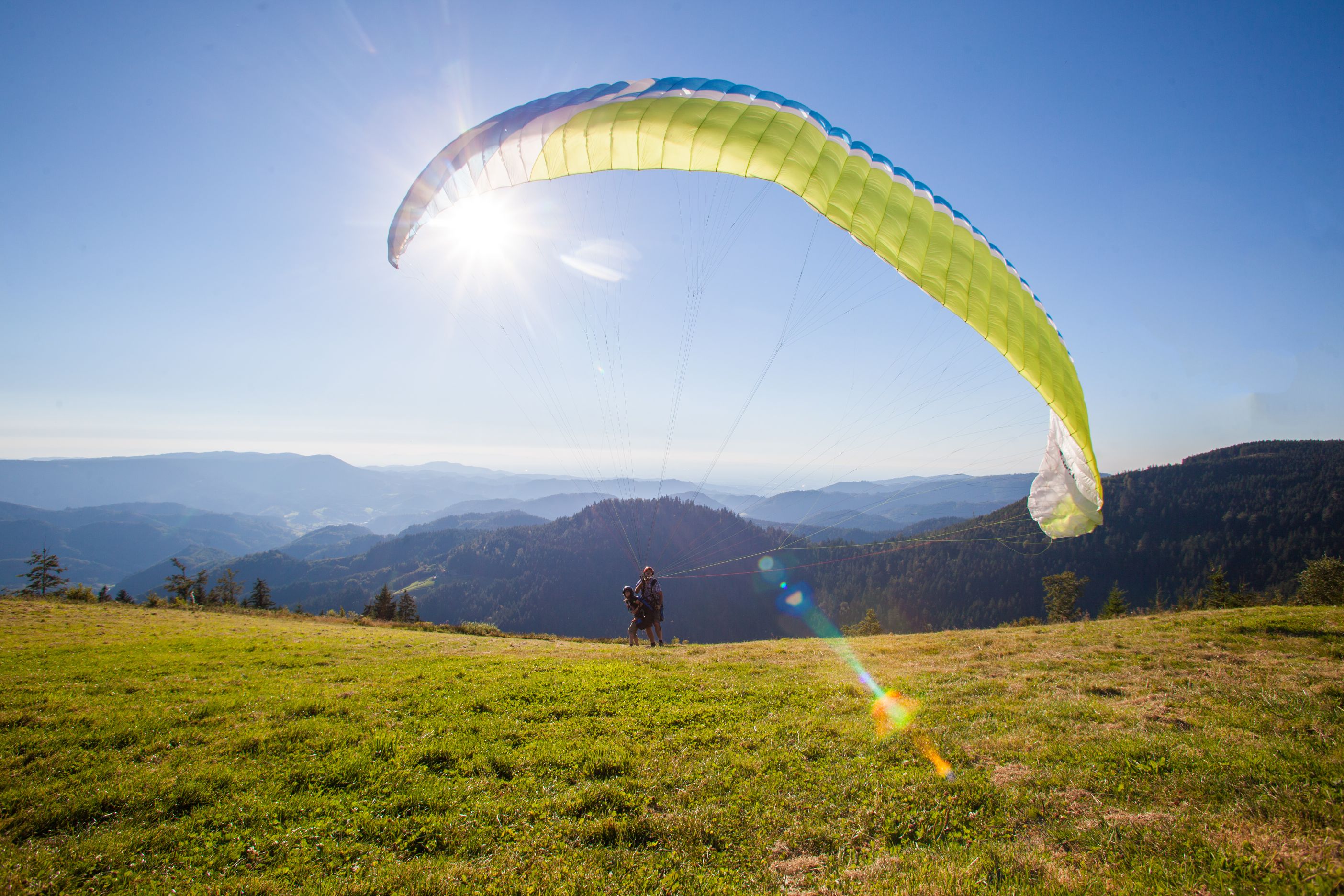 Gleitschirmflieger bei der Landung auf einer Wiese bei schönem Wetter