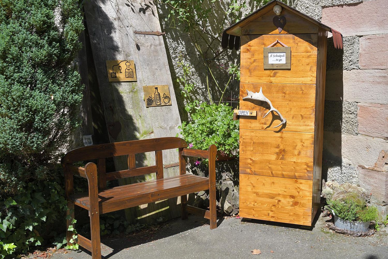 Schnapsbrunnen aus Holz mit einer Bank zum Hinsetzen